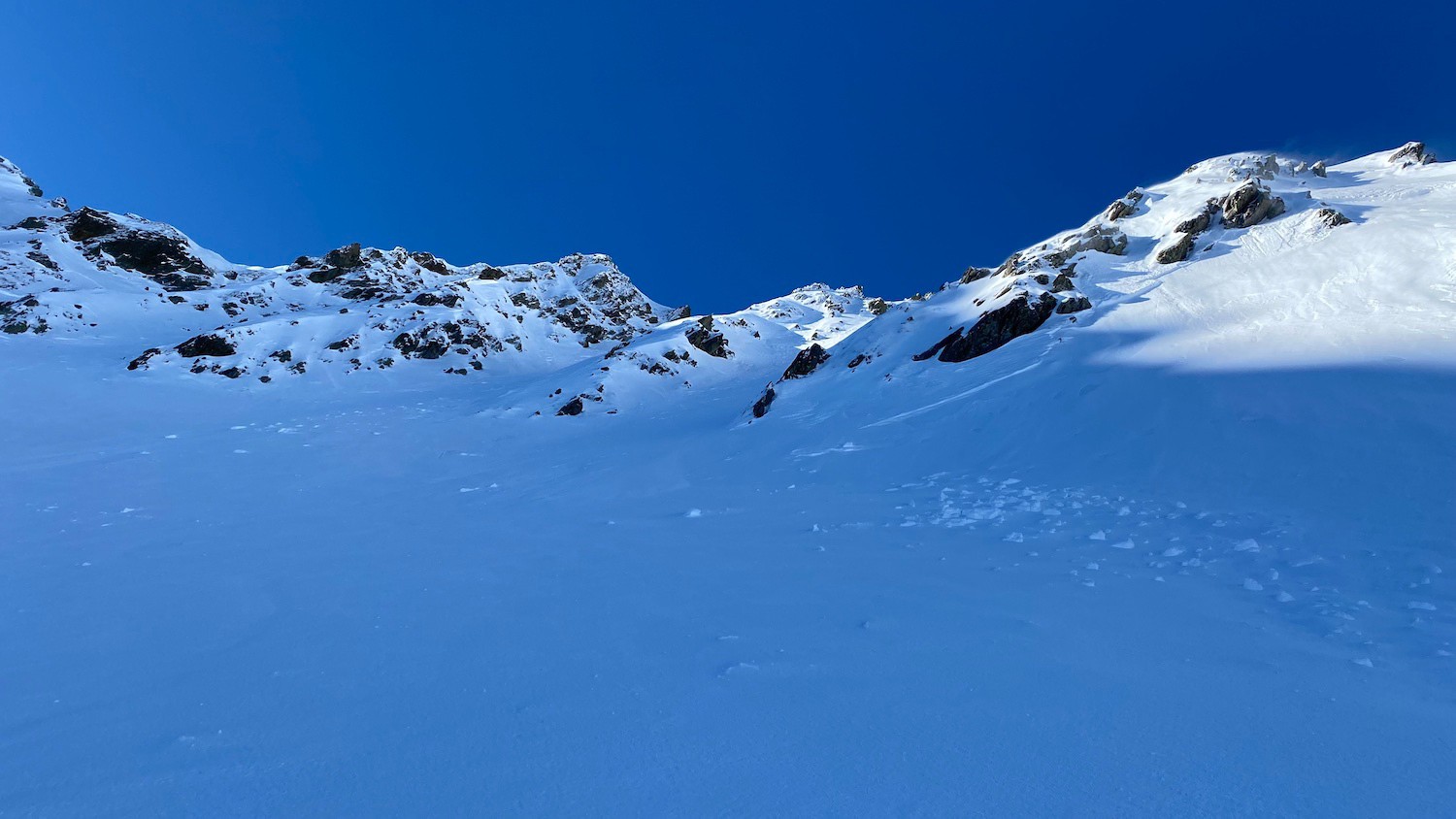 Le ski trouvé est au pied du couloir de droite, en arrière-plan, celui qui prend le soleil sur le haut.