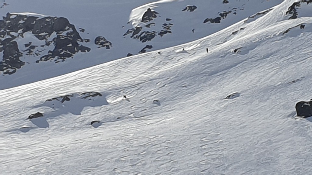 Vu du bas, un groupe de 3 skieurs suit