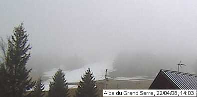 La Webcam : La Webcam du bas du domaine, la Blache (altitude : 1367m). Brouillard, une bande de neige sur la piste mollaret (enneigement artificiel).