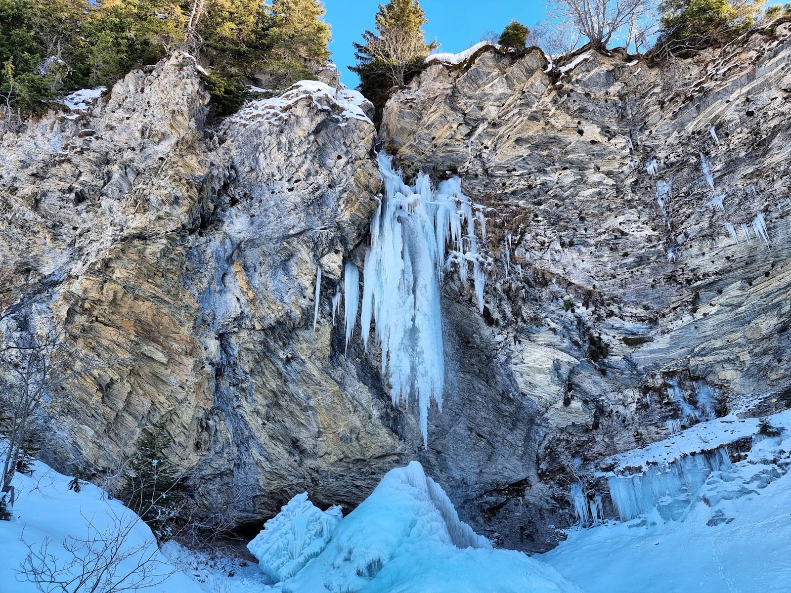 La cascade, pas encore totalement pétrifiée par le gel : l'eau jaillit entre colonnettes glacées et fragiles stalactites.