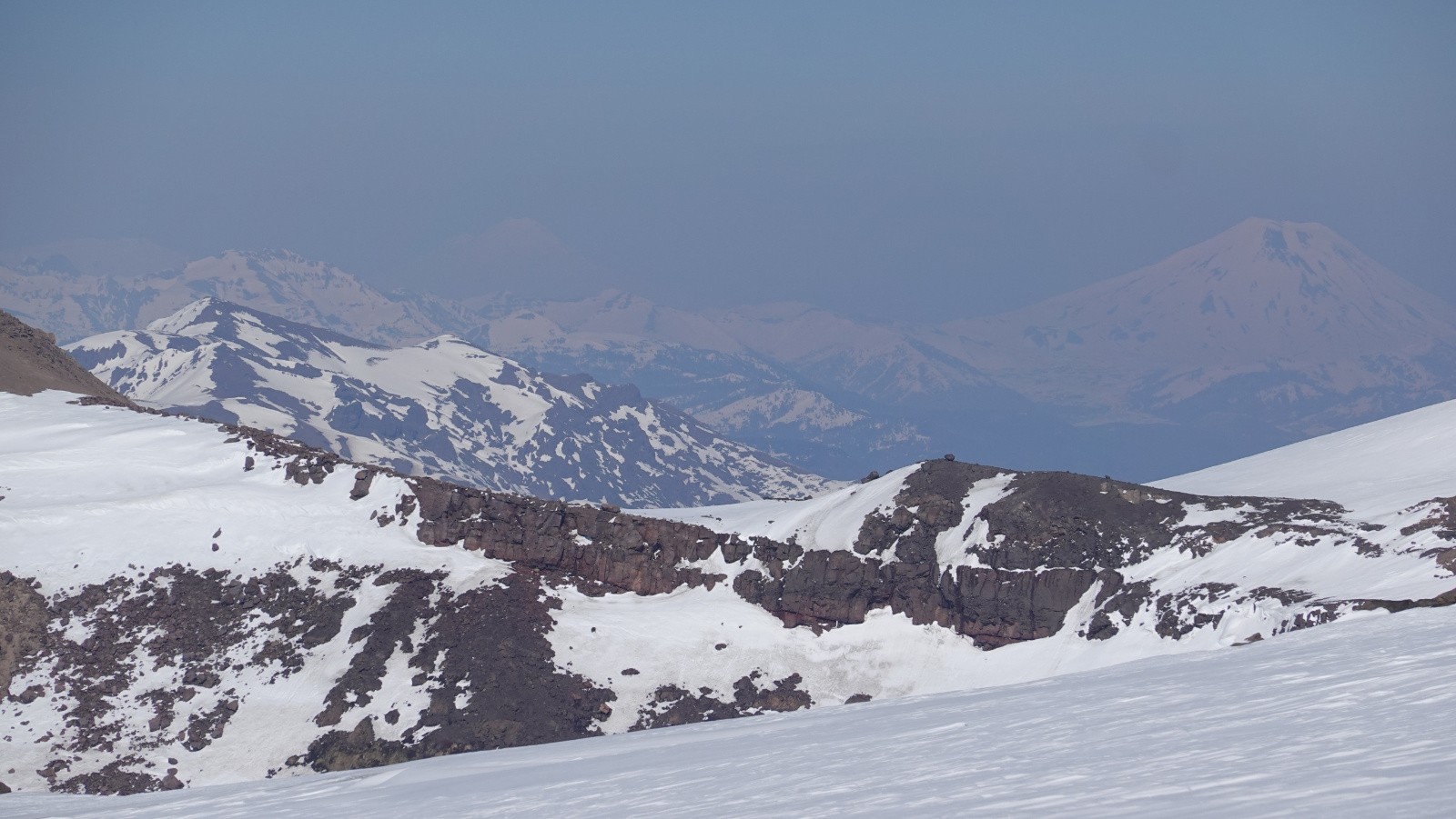 Panorama au téléobjectif et dans un ciel brumeux de la Sierra Nevada, les volcans Llaima et Lonquimay situés au Chili tout proche