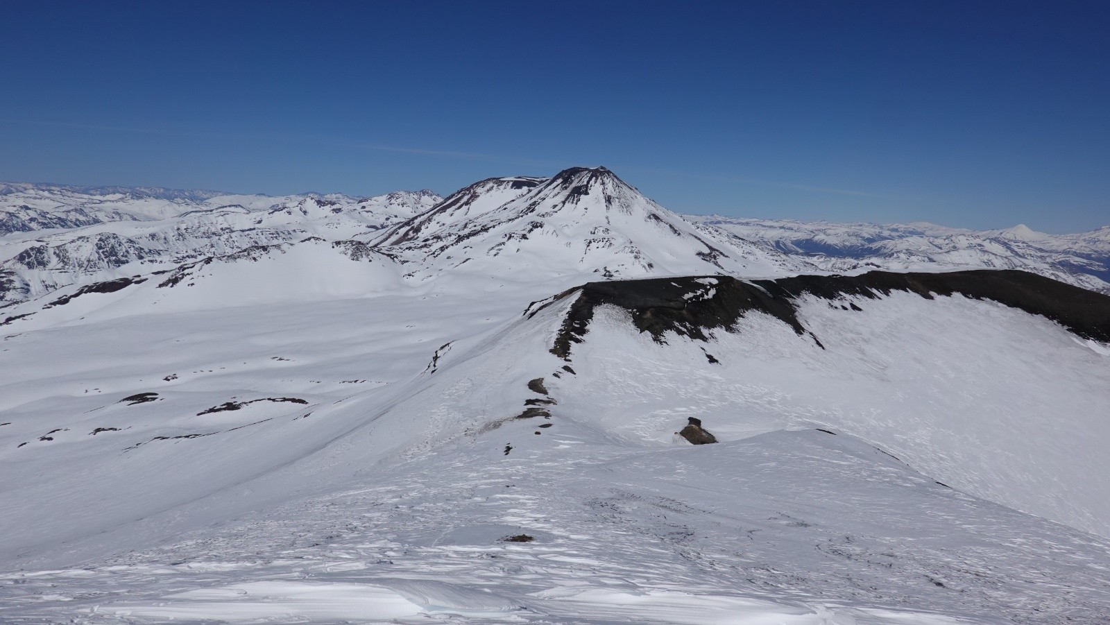 Coup d'œil dans le rétro depuis le col sous la première antécime du volcan Nevado : au premier plan le volcan Vidaurre et les volcans Chillan Nuevo y Viejo et le volcan Antuco au loin