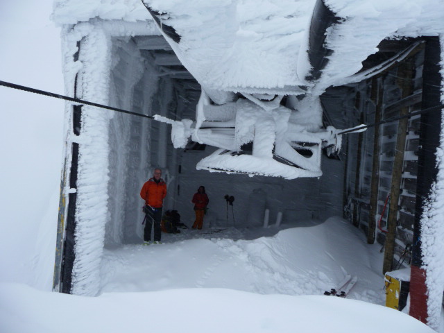 Pause déjeuner : Anne et Didier à l'abri du vent et de la neige au niveau de la gare d'arrivée d'un télésiège fermé depuis longtemps.