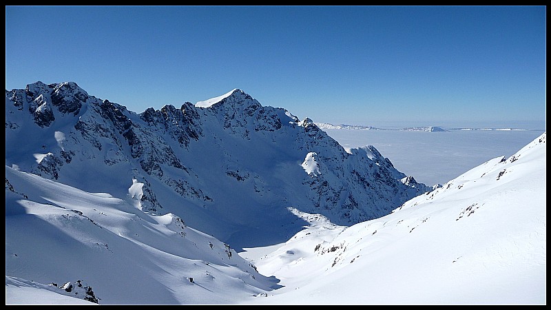Depuis le sommet, vue sur le Vercors au loin qui culmine au dessus de la mer de nuages. Au premier plan, le vallon du Lac Blanc.