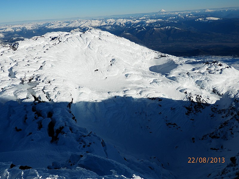 Vue sur le cratère du volcan : Llaima et au loin, le volcan Lanin dépassant les 3700m